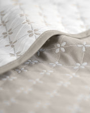 Close-up of the Juego de Edrecolcha Doble Vista Laurel by Intima Hogar, featuring soft quilted fabric with a subtle floral pattern in light beige and white tones; detailed stitching and texture make it perfect for an elegant colcha King or reversible colcha doble vista.