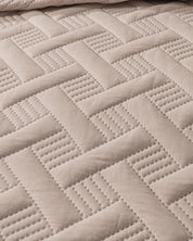 Close-up of the Juego de Edredón Ligero Esperanza by Intima Hogar, showcasing its quilted beige fabric with a herringbone pattern and stitched lines for a textured, structured look.
