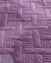 Close-up of the Edredón Ligero Provenza by Intima Hogar, featuring purple quilted fabric with a geometric pattern inspired by paisajes de Provenza—perfect for adding a textured, three-dimensional effect to your dormitorio.