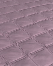 Close-up of the Juego de Edredón Ligero Lima by Intima Hogar, showing a soft mauve quilted fabric with a diamond-stitched pattern and smooth, padded texture.