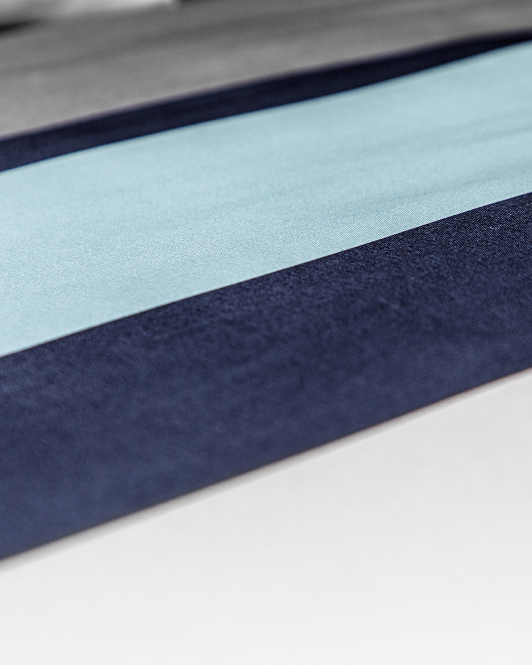 Close-up of the Juego de Edredón Luca by Intima Hogar, featuring a minimalist and abstract pattern with horizontal stripes in light blue, dark blue, gray, and white tones.