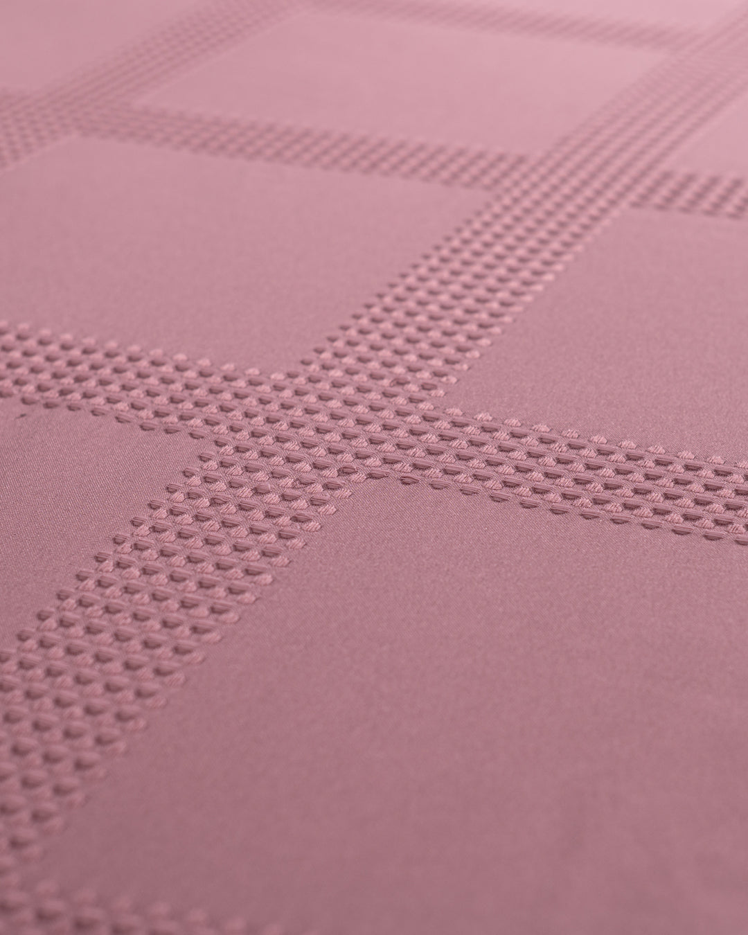 Close-up of the Juego de Edredón Luxury Pétalo by Intima Hogar, showcasing its textured mauve fabric with an embossed grid pattern and raised dots forming intersecting lines.