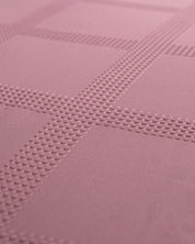 Close-up of the Juego de Edredón Luxury Pétalo by Intima Hogar, showcasing its textured mauve fabric with an embossed grid pattern and raised dots forming intersecting lines.