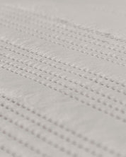 Close-up of the Juego de Edredón Velvet Silencio by Intima Hogar, featuring a white textured surface with small, evenly spaced raised dots in parallel lines for a subtle, elegant pattern.