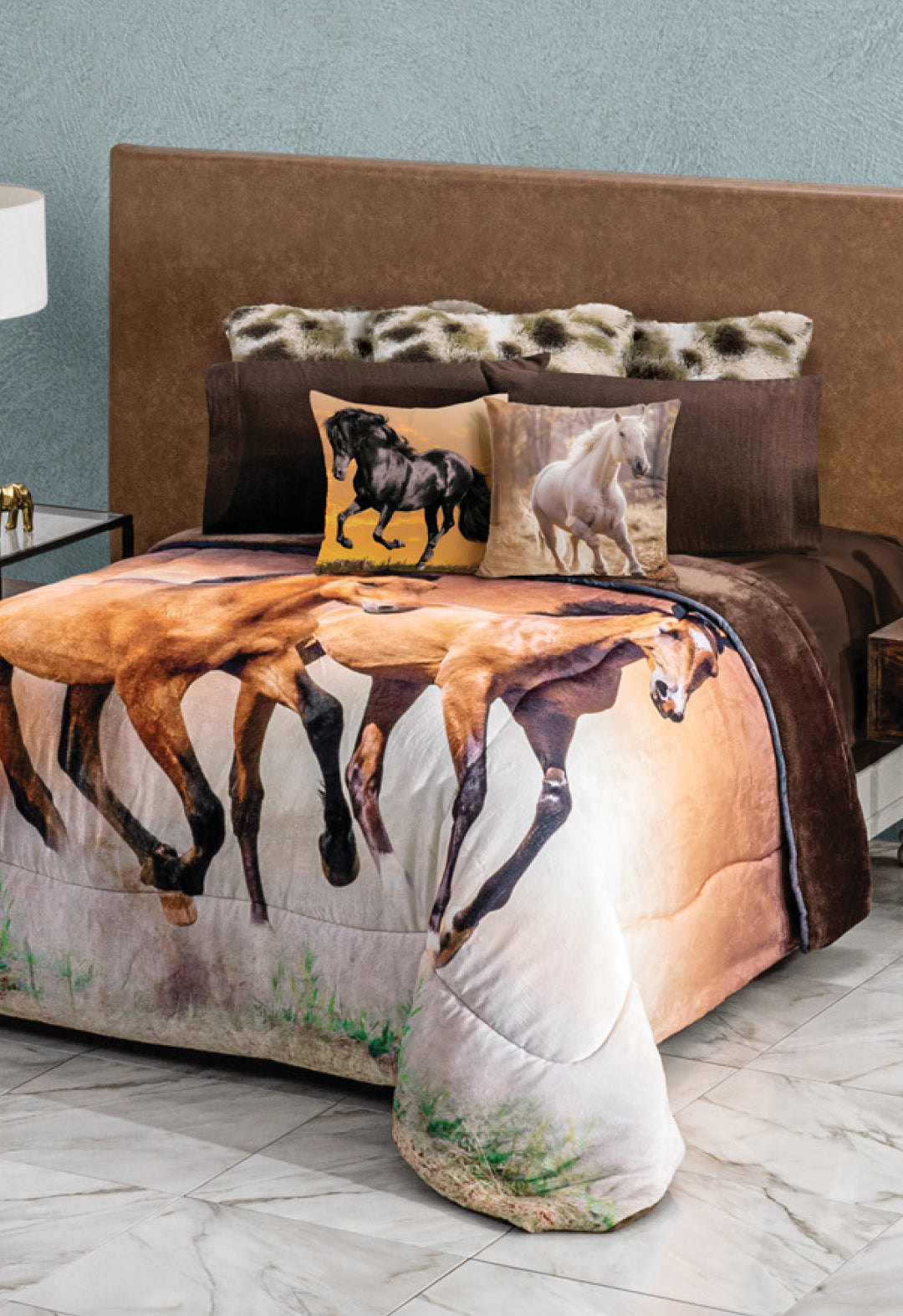 A neatly made bed with a horse-themed blanket and two Cojín Estampado Caballo by Intima Hogar rests against a brown upholstered headboard. The modern room, with marble floor and lamp-topped side table, logra un diseño elegante en la decoración cama.