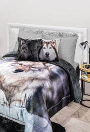 A bed with a comforter and pillows featuring realistic lobo faces adds a visual accent to a modern bedroom, next to a nightstand with books and the Cojín Estampado Lobo by Intima Hogar placed under the lamp.