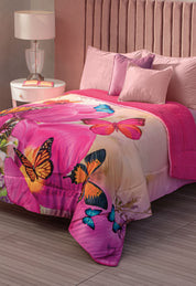 A neatly made bed with Intima Hogar’s Cobertor Digital Ultra Suave Mariposa-Desc, pink pillows, a velvet headboard, a bedside table with a lamp, and a soft pink franela sherpa blanket.
